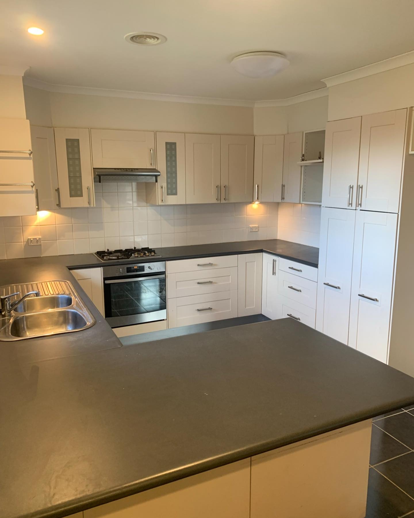 Before: original Holt kitchen with beige cabinets and tile splashback